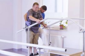 pacjent na zabiegu fizjoterapii wchodzi po schodach przy pomocy fizjoterapeuty